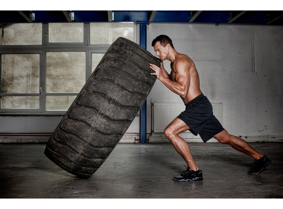 Moški, ki pred seboj potiska pnevmatike